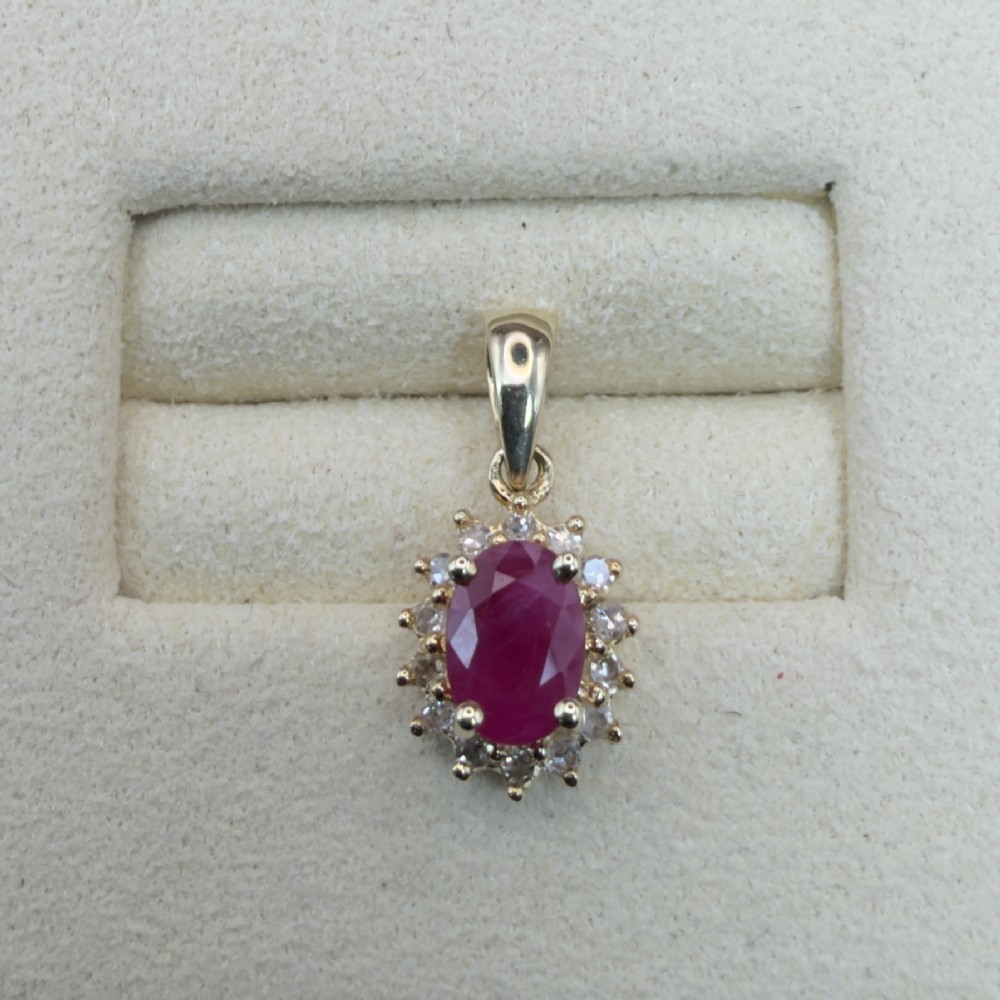 A 14ct yellow gold cluster pendant featuring an oval-cut red ruby framed by small round diamonds. View V