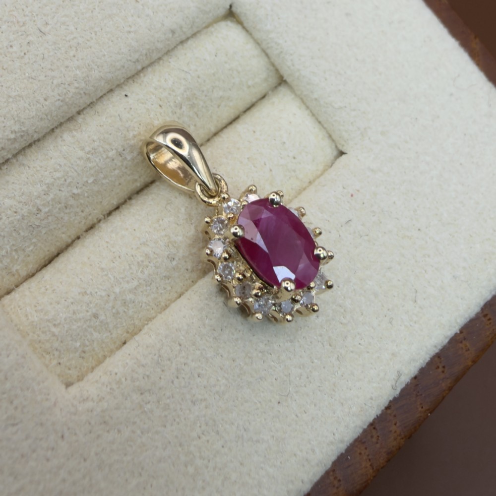 A 14ct yellow gold cluster pendant featuring an oval-cut red ruby framed by small round diamonds. View VII