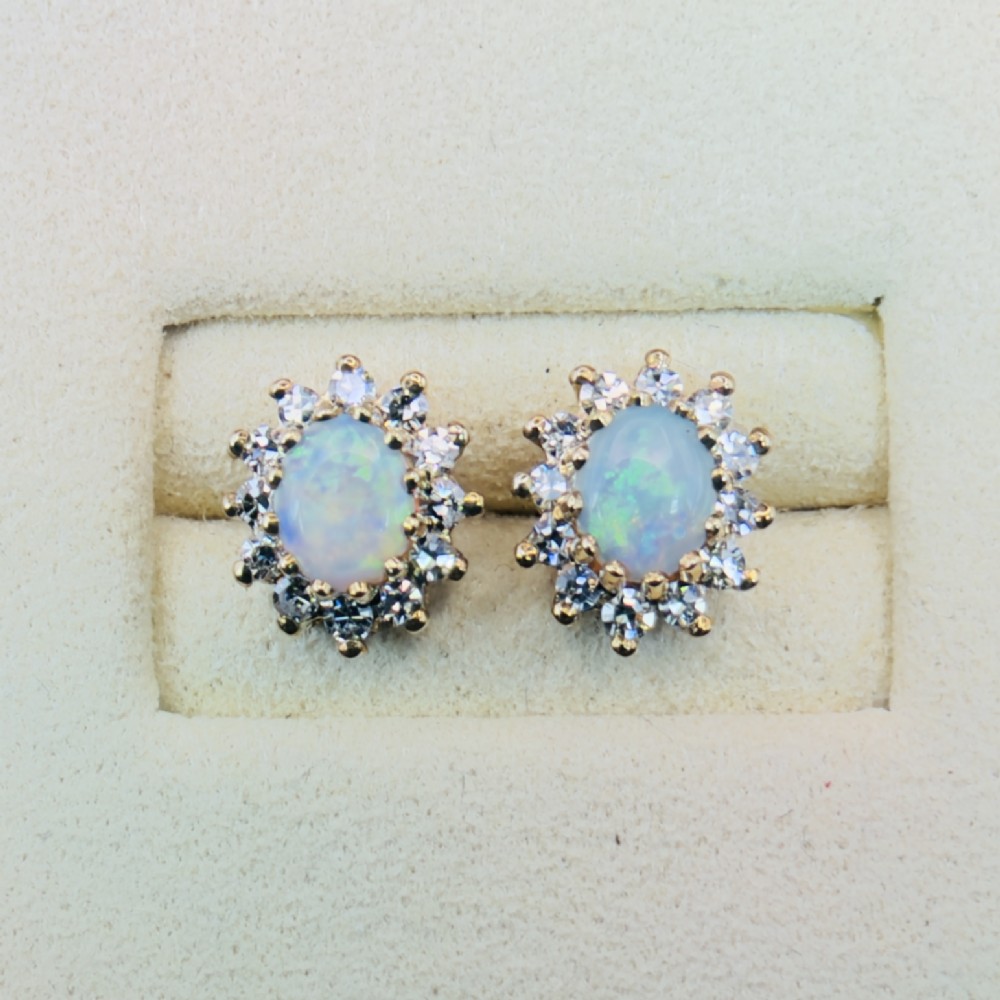 A pair of 9ct yellow gold stud earrings featuring central oval cabochon opals surrounded by a halo of small brilliant-cut diamonds. View III