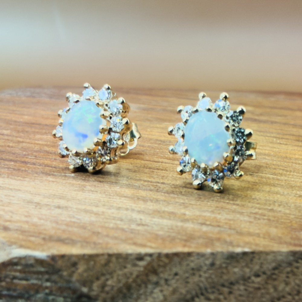 A pair of 9ct yellow gold stud earrings featuring central oval cabochon opals surrounded by a halo of small brilliant-cut diamonds. View VIII