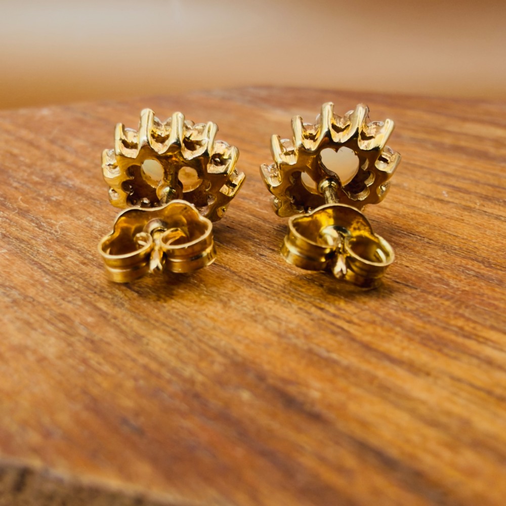 A pair of 9ct yellow gold stud earrings featuring central oval cabochon opals surrounded by a halo of small brilliant-cut diamonds. View IX