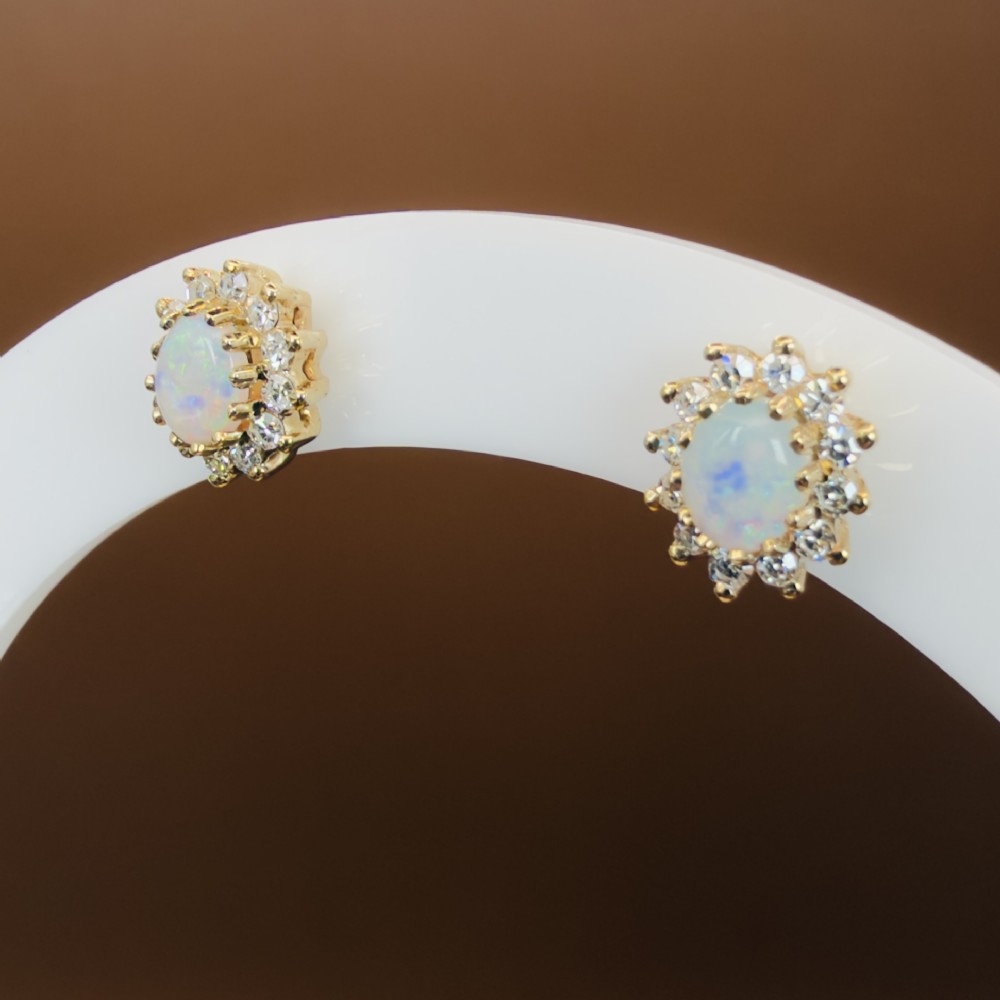 A pair of 9ct yellow gold stud earrings featuring central oval cabochon opals surrounded by a halo of small brilliant-cut diamonds. View XII
