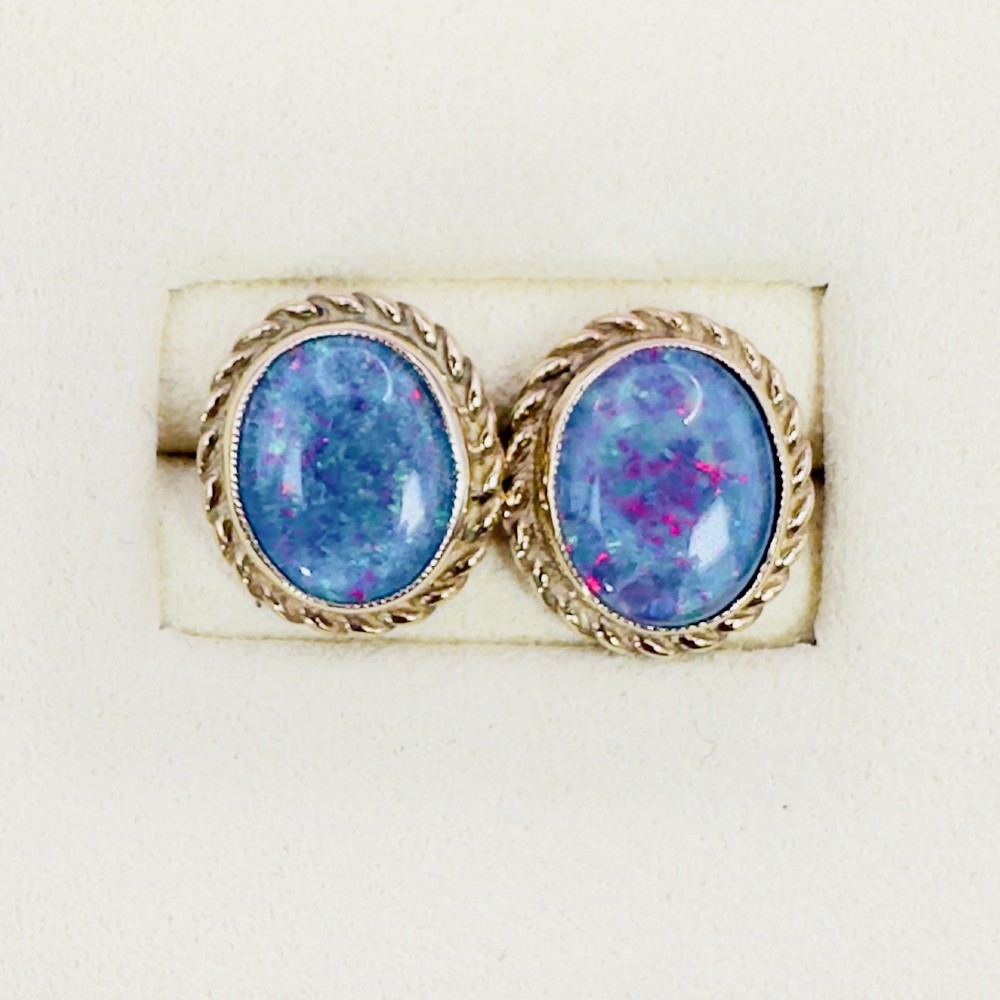 A pair of oval 9ct yellow gold stud earrings featuring iridescent black opal doublets surrounded by a twisted rope border. View III