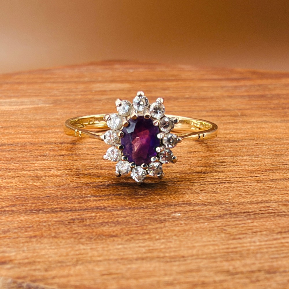 A vintage 9ct yellow gold ring featuring a central oval purple amethyst framed by a halo cluster of round white spinel gemstones. View VIII
