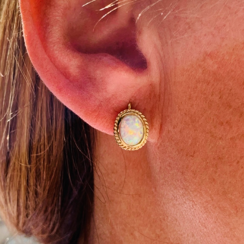 A pair of 14ct yellow gold stud earrings featuring oval cabochon opals surrounded by a textured rope-twist border. View VI