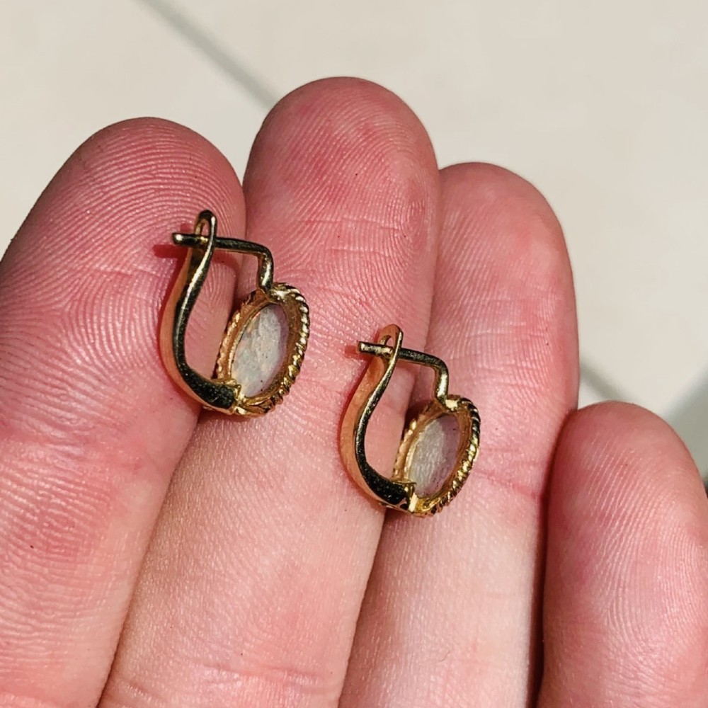 A pair of 14ct yellow gold stud earrings featuring oval cabochon opals surrounded by a textured rope-twist border. View VII