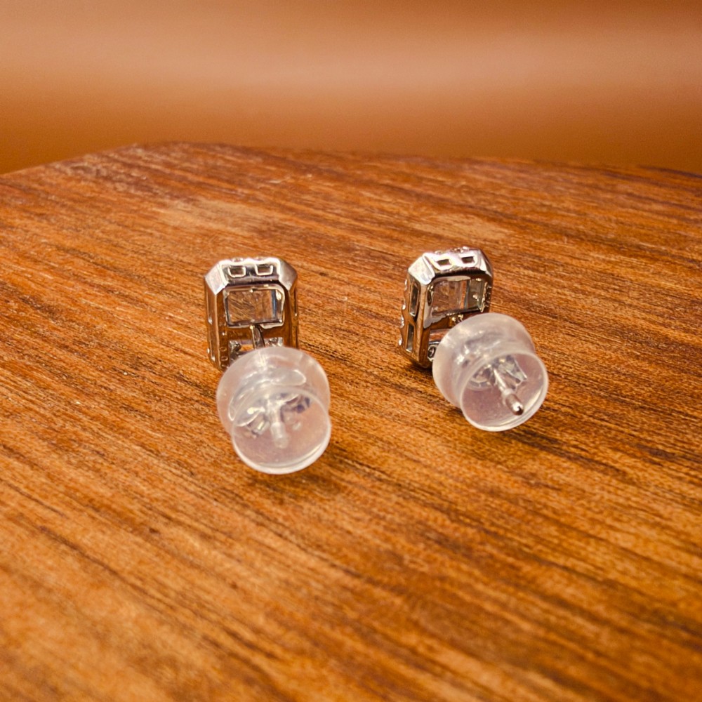 A pair of platinum stud earrings featuring emerald-cut light blue aquamarines surrounded by a border of brilliant-cut diamonds. View VII