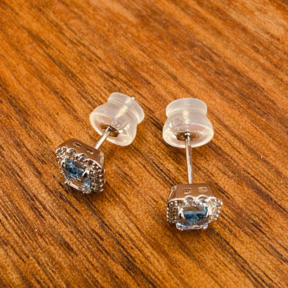 A pair of platinum stud earrings featuring emerald-cut light blue aquamarines surrounded by a border of brilliant-cut diamonds. View VIII