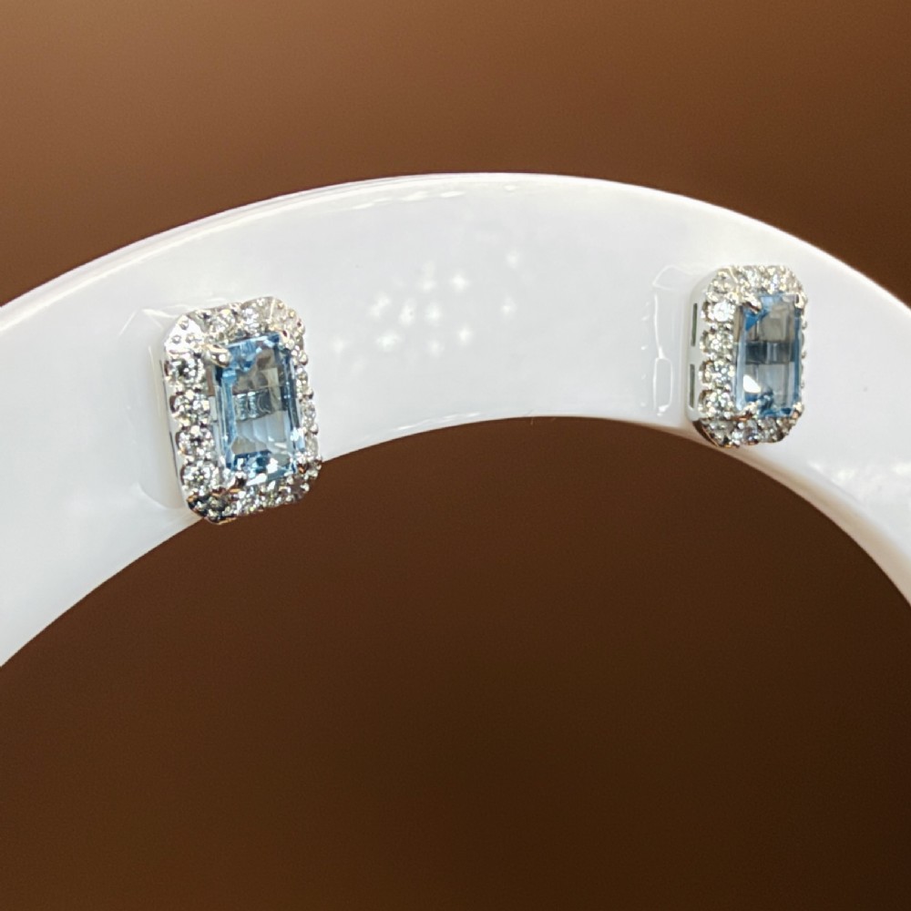 A pair of platinum stud earrings featuring emerald-cut light blue aquamarines surrounded by a border of brilliant-cut diamonds. View XI