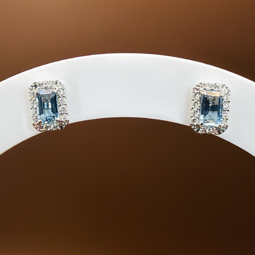 A pair of platinum stud earrings featuring emerald-cut light blue aquamarines surrounded by a border of brilliant-cut diamonds. View XII