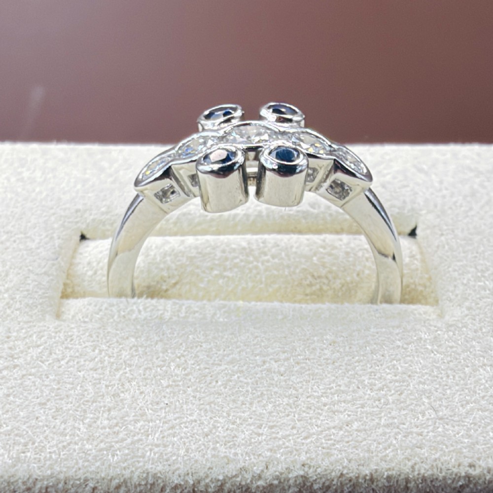A platinum ring crafted with five bezel-set diamonds in a central horizontal row, flanked by four small round blue sapphires. View V