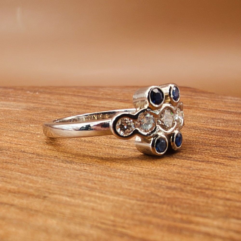 A platinum ring crafted with five bezel-set diamonds in a central horizontal row, flanked by four small round blue sapphires. View VII