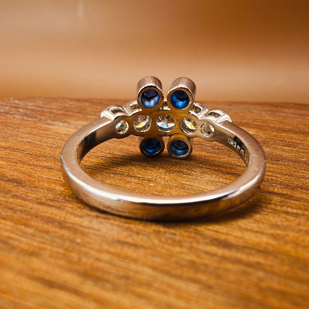 A platinum ring crafted with five bezel-set diamonds in a central horizontal row, flanked by four small round blue sapphires. View VIII