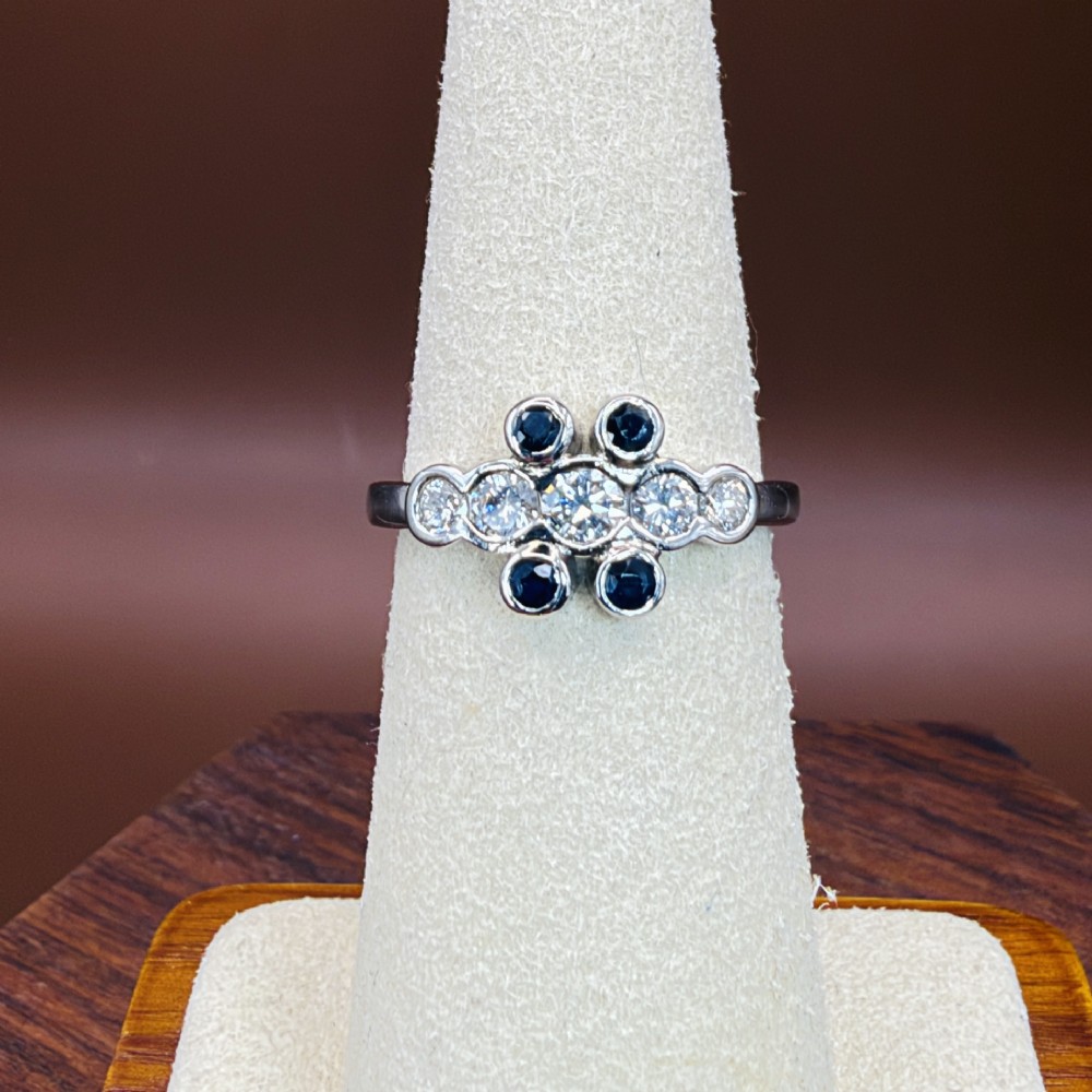 A platinum ring crafted with five bezel-set diamonds in a central horizontal row, flanked by four small round blue sapphires. View IX