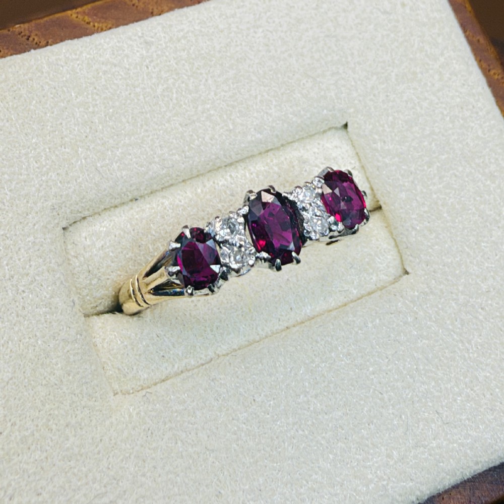 An 18ct yellow gold ring featuring three oval red rubies separated by pairs of small diamonds set in a claw setting. View IV