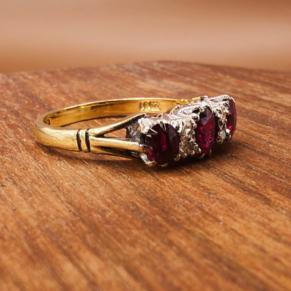 An 18ct yellow gold ring featuring three oval red rubies separated by pairs of small diamonds set in a claw setting. View VII