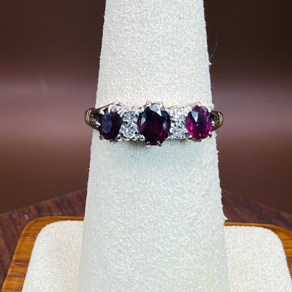 An 18ct yellow gold ring featuring three oval red rubies separated by pairs of small diamonds set in a claw setting. View VIII