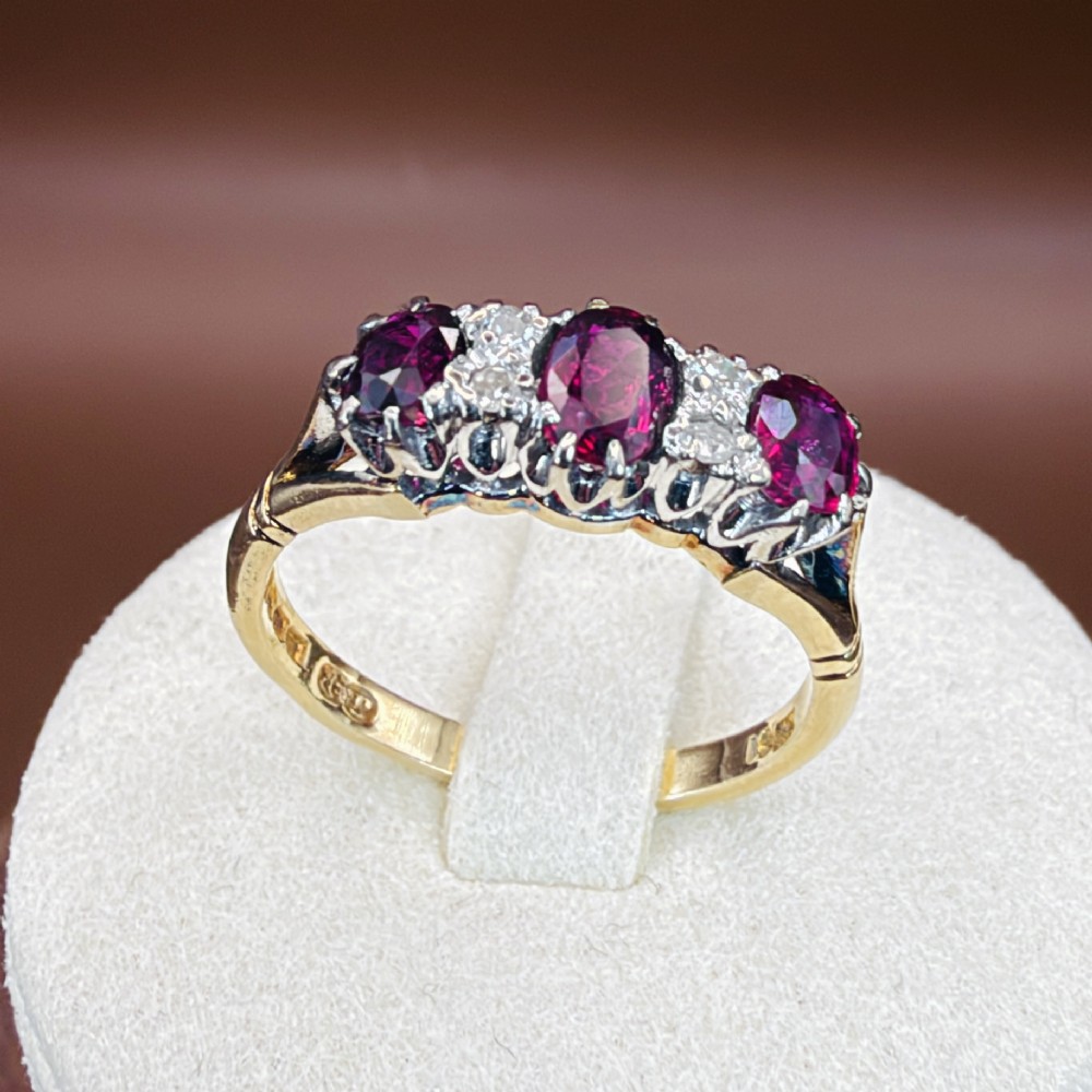 An 18ct yellow gold ring featuring three oval red rubies separated by pairs of small diamonds set in a claw setting. View XII