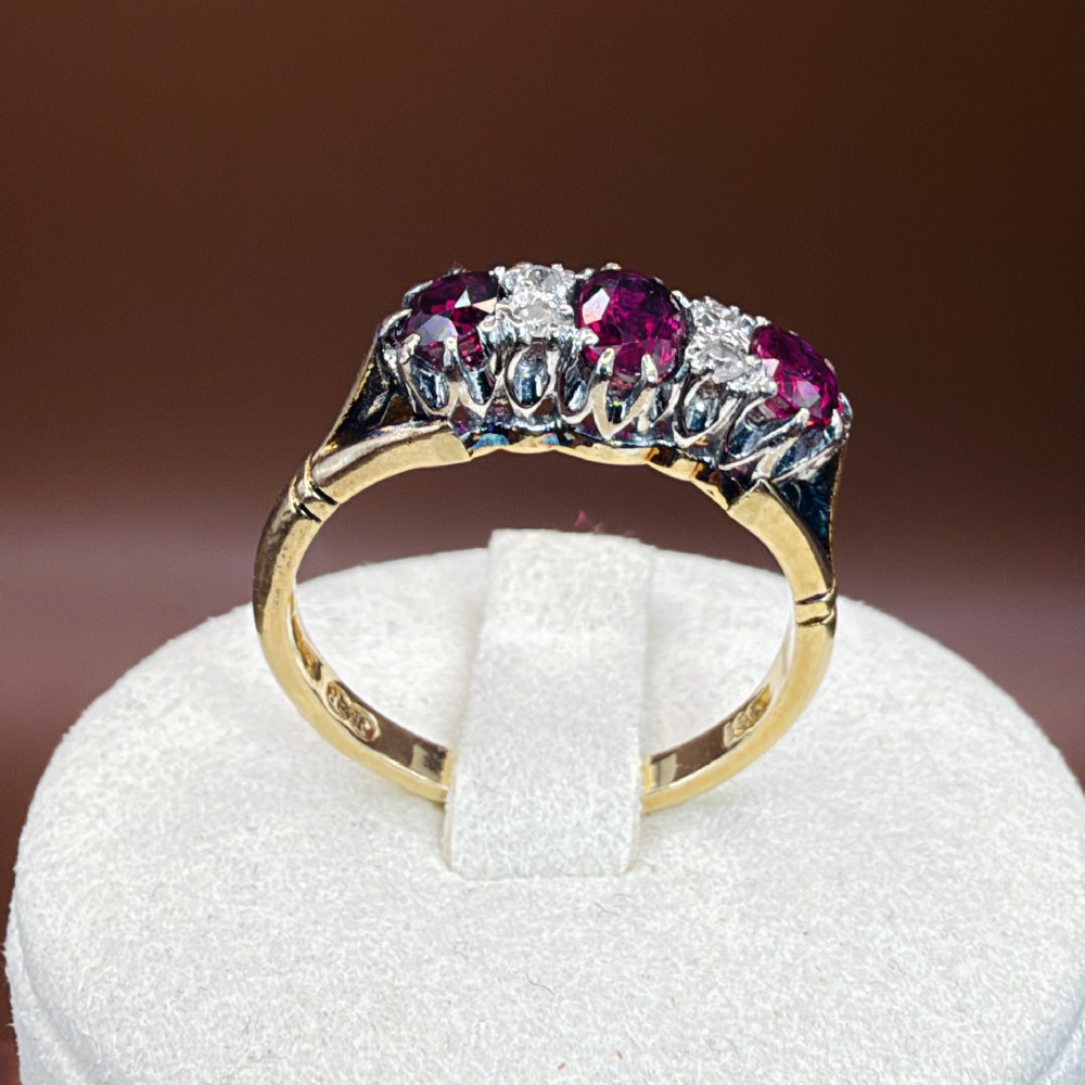 An 18ct yellow gold ring featuring three oval red rubies separated by pairs of small diamonds set in a claw setting. View XIV