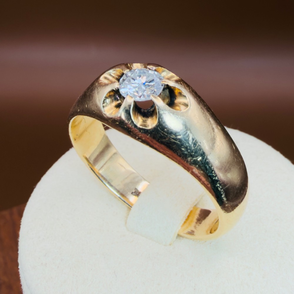 An 18ct yellow gold mens solitaire ring featuring a single diamond mounted in a carved starburst setting.