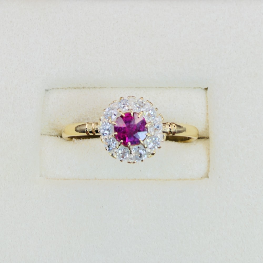 An 18ct yellow gold Victorian ring featuring a central round red ruby surrounded by a halo of hand-cut diamonds. View II