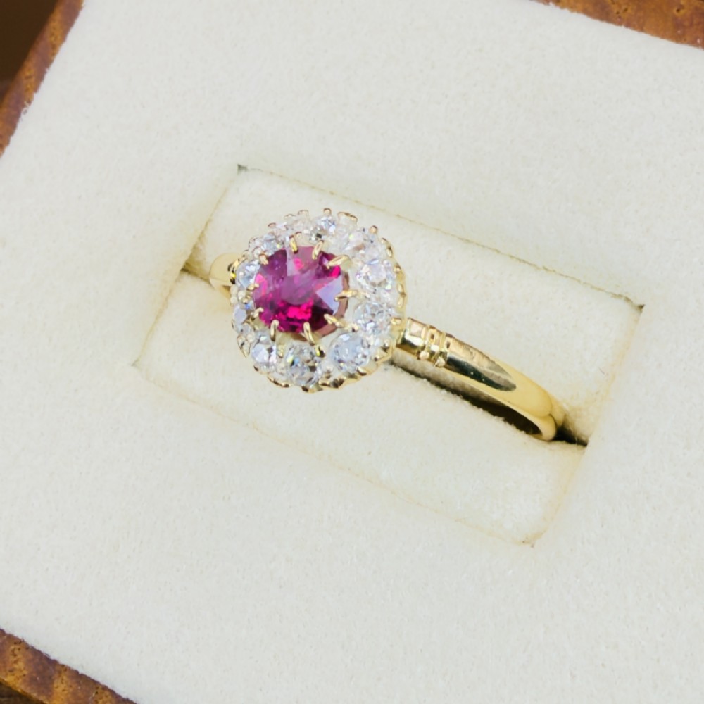 An 18ct yellow gold Victorian ring featuring a central round red ruby surrounded by a halo of hand-cut diamonds. View III