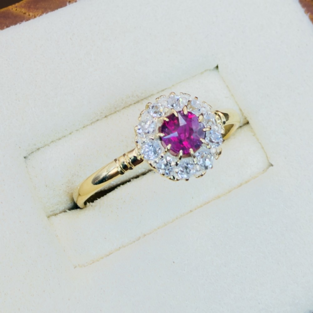 An 18ct yellow gold Victorian ring featuring a central round red ruby surrounded by a halo of hand-cut diamonds. View IV