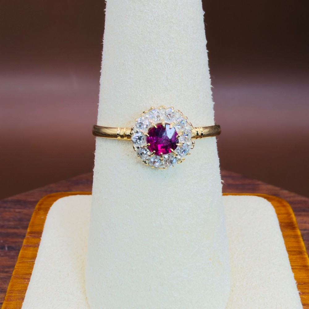 An 18ct yellow gold Victorian ring featuring a central round red ruby surrounded by a halo of hand-cut diamonds. View VIII