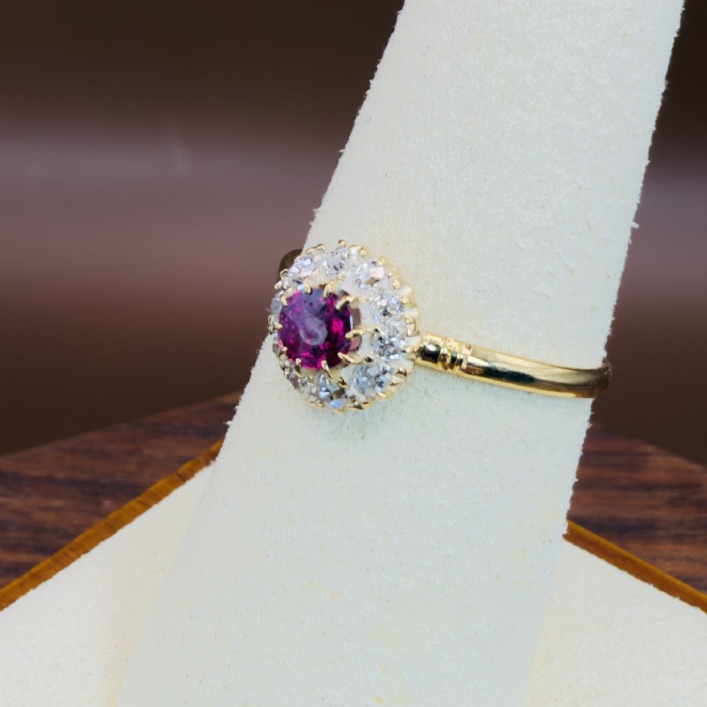 An 18ct yellow gold Victorian ring featuring a central round red ruby surrounded by a halo of hand-cut diamonds. View IX