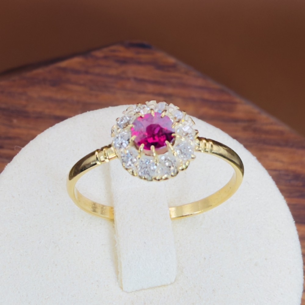 An 18ct yellow gold Victorian ring featuring a central round red ruby surrounded by a halo of hand-cut diamonds. View XI