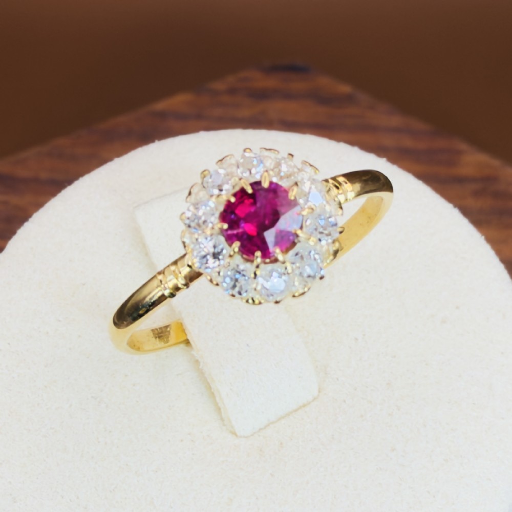 An 18ct yellow gold Victorian ring featuring a central round red ruby surrounded by a halo of hand-cut diamonds. View XII
