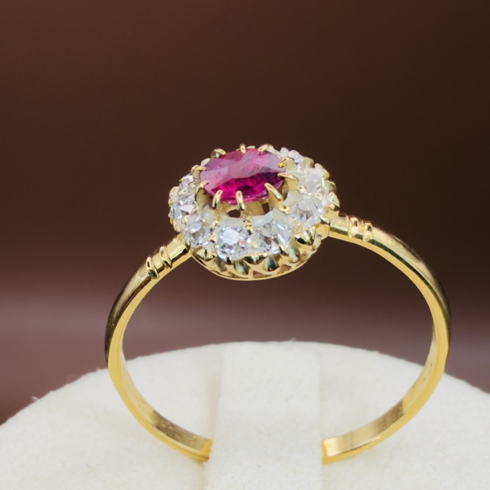 An 18ct yellow gold Victorian ring featuring a central round red ruby surrounded by a halo of hand-cut diamonds. View XIII