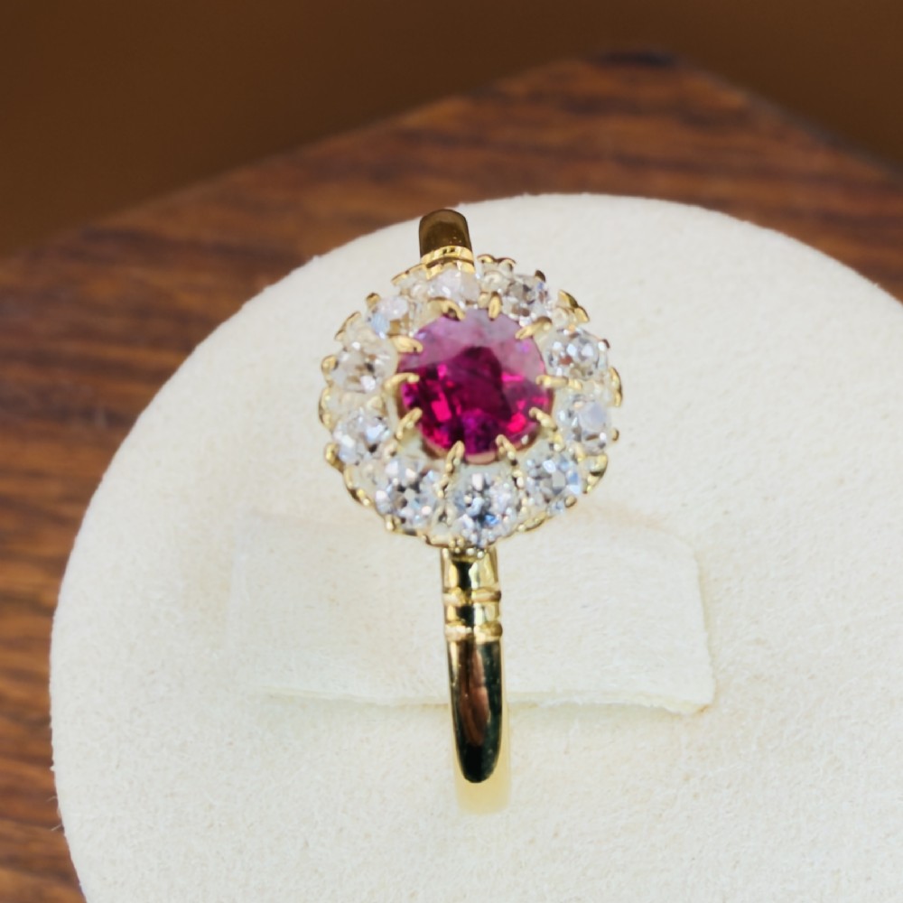 An 18ct yellow gold Victorian ring featuring a central round red ruby surrounded by a halo of hand-cut diamonds. View XIV
