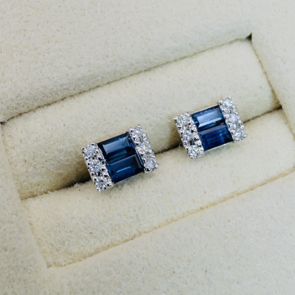 A pair of 9ct white gold stud earrings featuring two central emerald-cut blue sapphires flanked by small round diamonds. View III