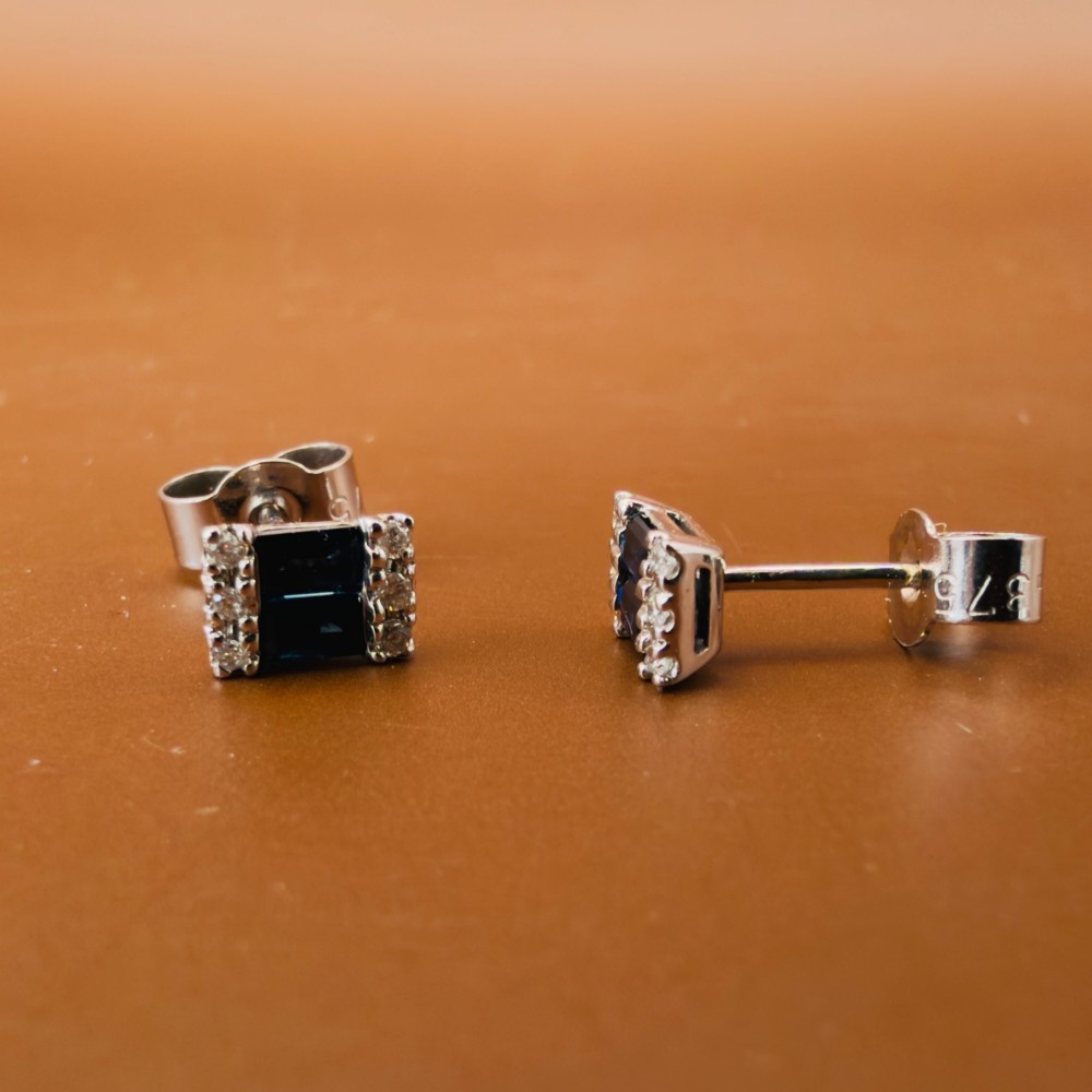 A pair of 9ct white gold stud earrings featuring two central emerald-cut blue sapphires flanked by small round diamonds. View VII