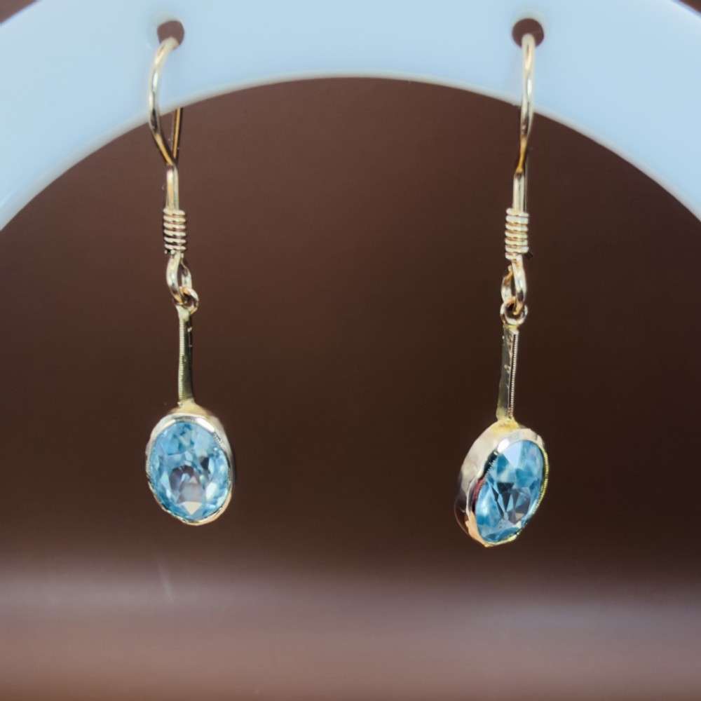 A pair of 9ct yellow gold Art Deco drop earrings featuring oval-cut light blue zircons suspended from vertical gold bars and shepherd hook wires. View V