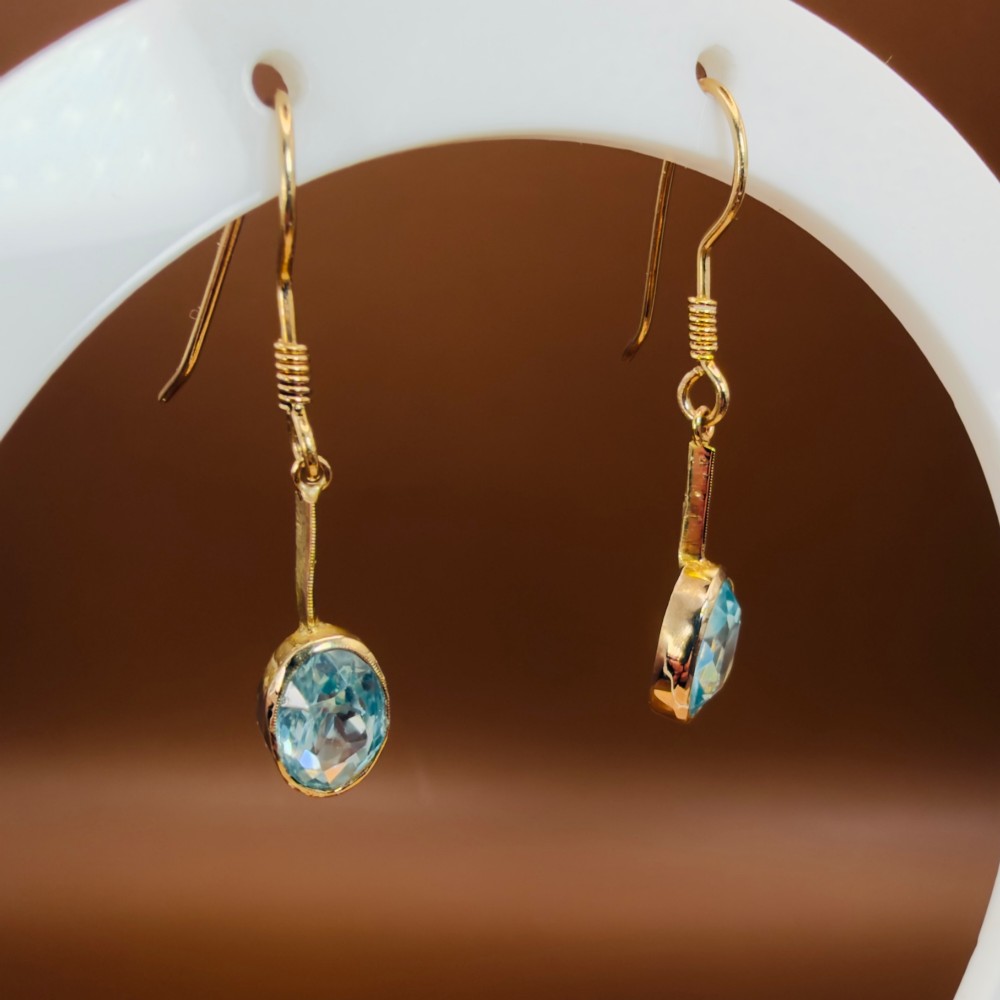 A pair of 9ct yellow gold Art Deco drop earrings featuring oval-cut light blue zircons suspended from vertical gold bars and shepherd hook wires. View VII
