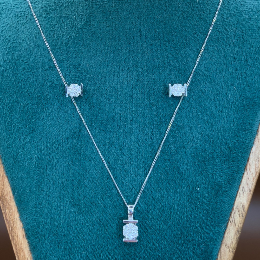 A white gold jewellery set consisting of a fine chain necklace with a round diamond cluster pendant and matching cluster stud earrings. View II
