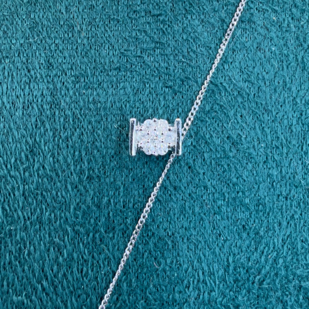 A white gold jewellery set consisting of a fine chain necklace with a round diamond cluster pendant and matching cluster stud earrings. View IV