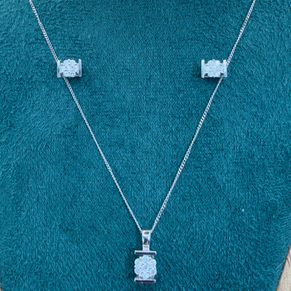 A white gold jewellery set consisting of a fine chain necklace with a round diamond cluster pendant and matching cluster stud earrings.