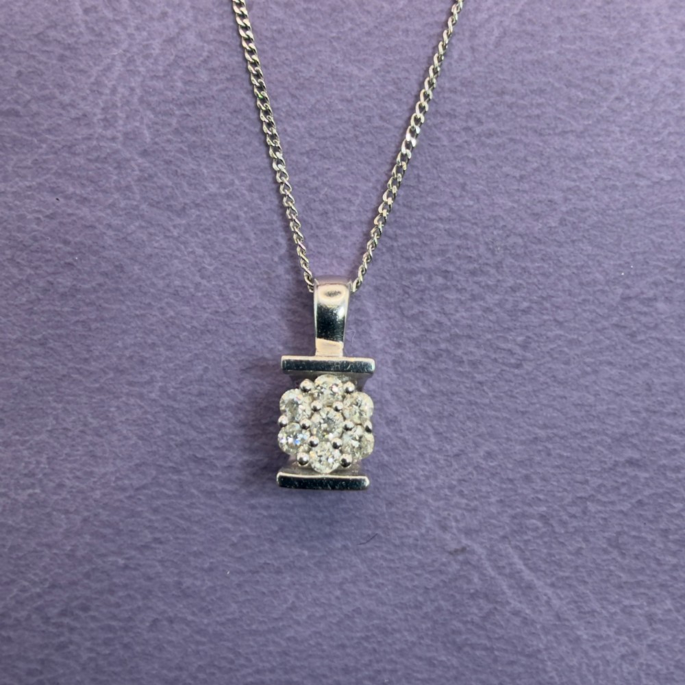 A white gold jewellery set consisting of a fine chain necklace with a round diamond cluster pendant and matching cluster stud earrings. View X