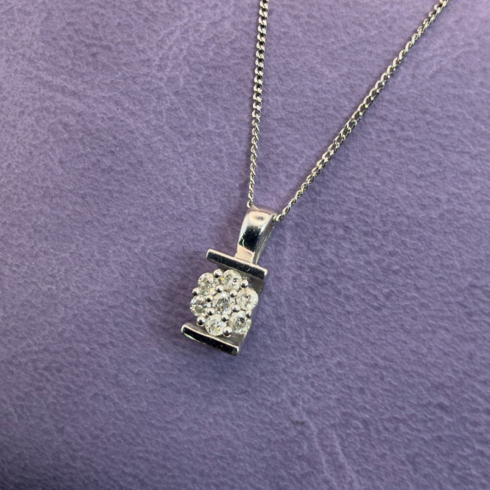 A white gold jewellery set consisting of a fine chain necklace with a round diamond cluster pendant and matching cluster stud earrings. View XI