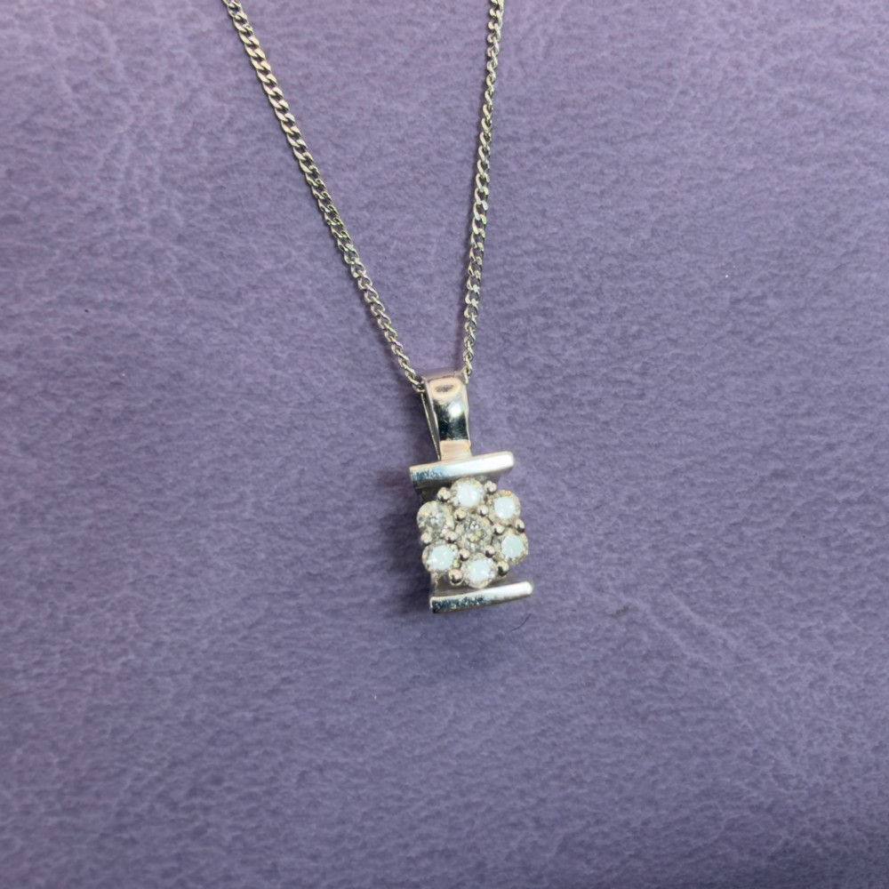 A white gold jewellery set consisting of a fine chain necklace with a round diamond cluster pendant and matching cluster stud earrings. View XII