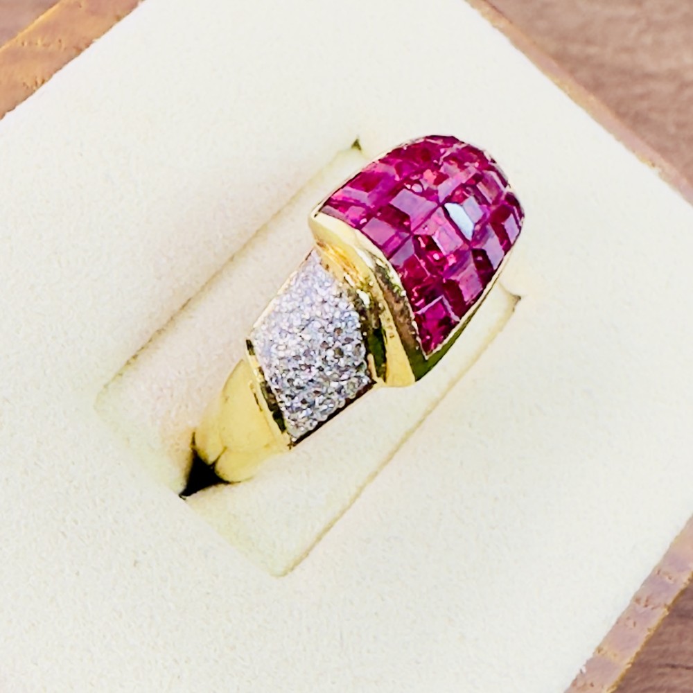 An 18ct yellow gold dress ring featuring a curved panel of princess cut red rubies alongside diamond set shoulders. View IV