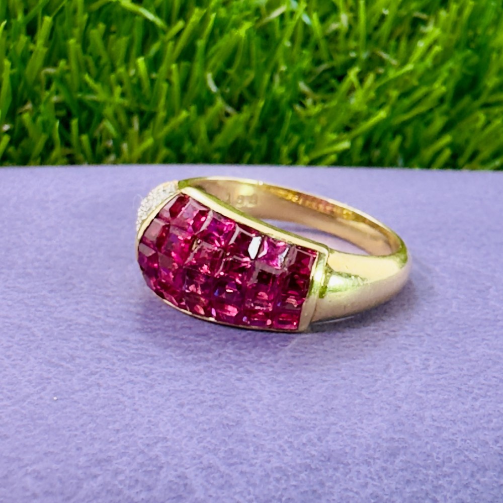 An 18ct yellow gold dress ring featuring a curved panel of princess cut red rubies alongside diamond set shoulders. View VI