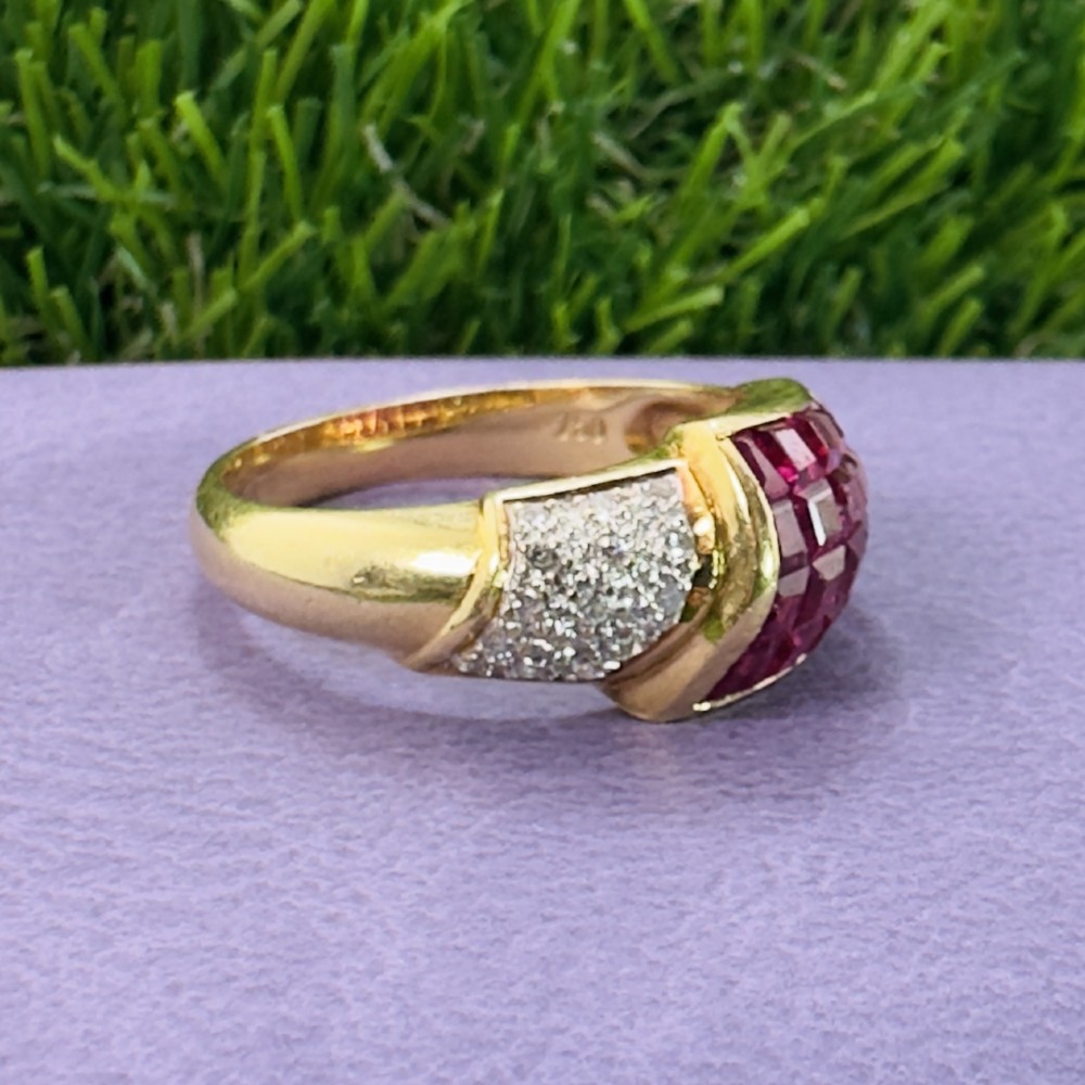 An 18ct yellow gold dress ring featuring a curved panel of princess cut red rubies alongside diamond set shoulders. View VII