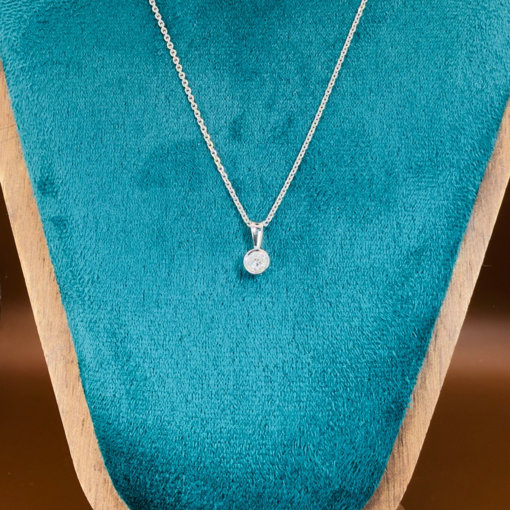 A single round brilliant-cut diamond set in a white gold bezel pendant suspended from a fine white gold chain. View VII