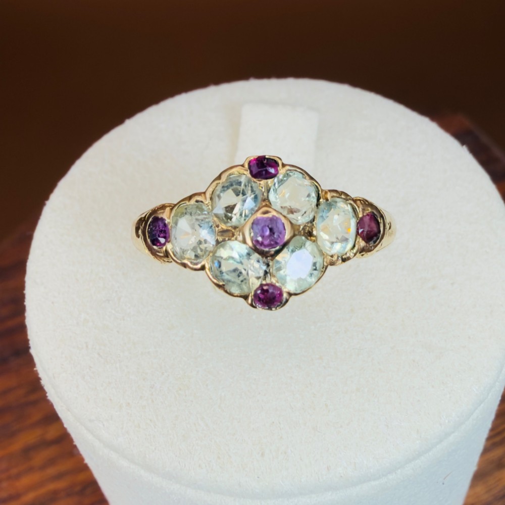 An 18ct yellow gold early Victorian cluster ring set with pale green spinels, rubies, and purple almandine garnets.