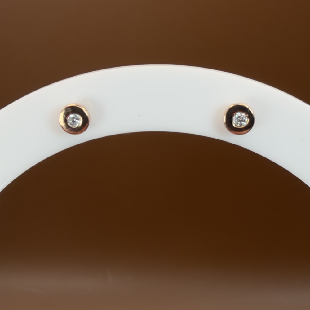 A pair of circular 9ct rose gold stud earrings featuring round bezel-set natural diamonds. View II