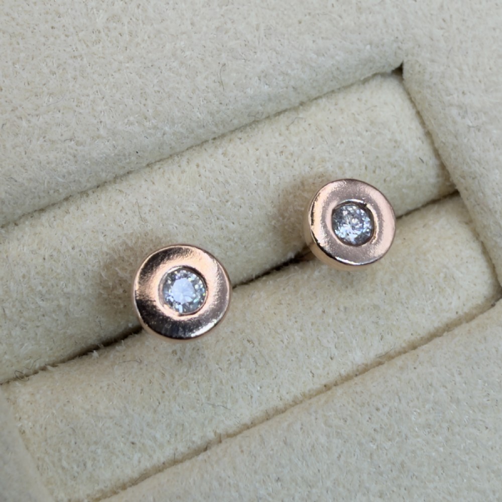 A pair of circular 9ct rose gold stud earrings featuring round bezel-set natural diamonds. View VIII